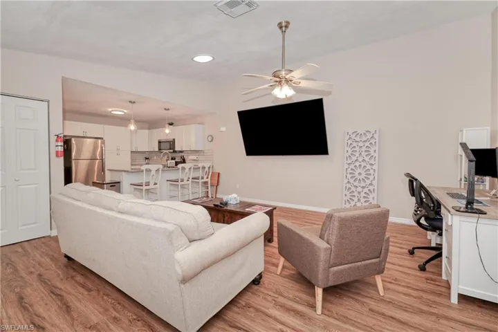 Living room with light hardwood / wood-style floors, sink, ceiling fan, and lofted ceiling