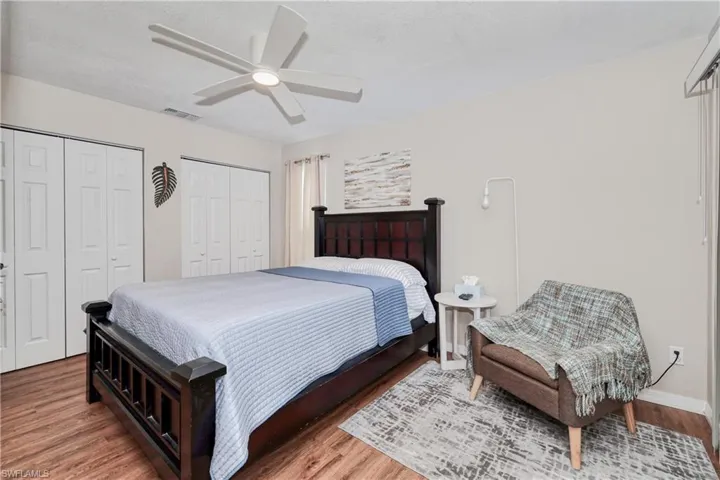 Bedroom with two closets, ceiling fan, and hardwood / wood-style floors