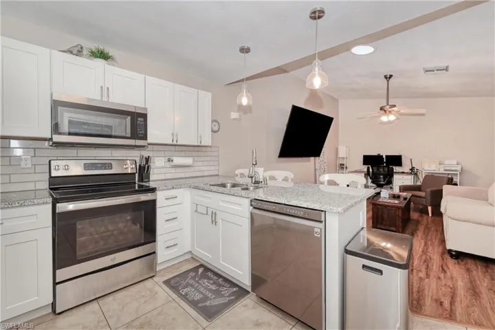 Kitchen featuring ceiling fan, kitchen peninsula, sink, white cabinetry, and appliances with stainless steel finishes
