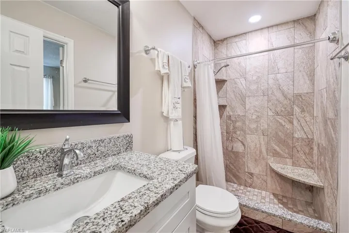 Bathroom with vanity, toilet, and a shower with shower curtain