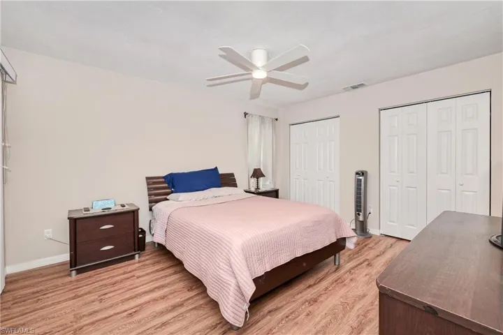Bedroom with multiple closets, wood-type flooring, and ceiling fan