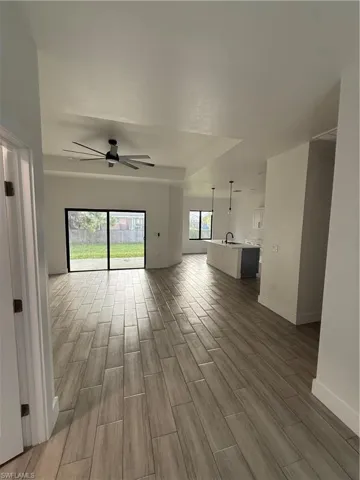 Unfurnished living room with wood tiled floors, a ceiling fan, and a tray ceiling