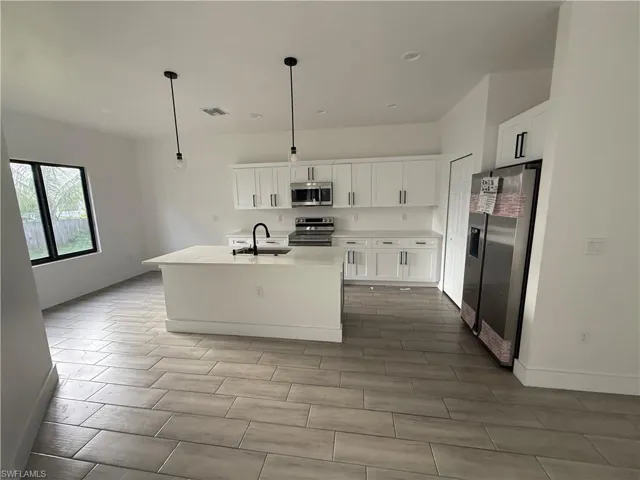 Kitchen with white cabinetry, a center island with sink, stainless steel appliances, pendant lighting, and recessed lighting