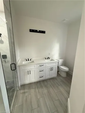 Bathroom featuring double vanity, a stall shower, and wood finish floors