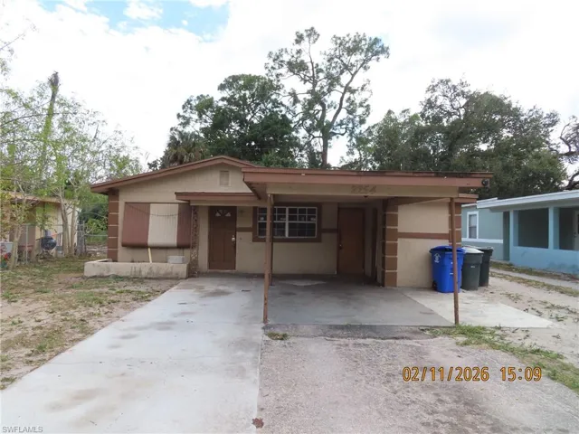 View of front of property with driveway, a carport, and stucco siding