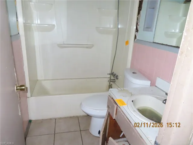 Bathroom with vanity, light tile patterned flooring, tub / shower combination, and tile walls
