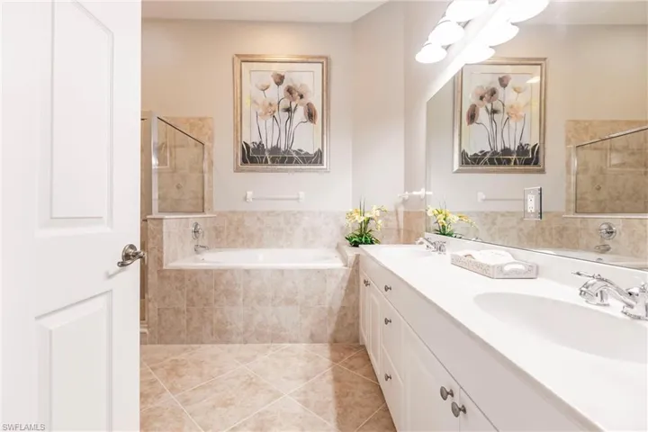 Full bath featuring a garden tub, double vanity, light tile patterned floors, and a tile shower