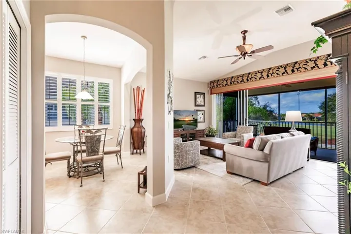 Living room with vaulted ceiling, tile patterned floors, ceiling fan, and arched walkways