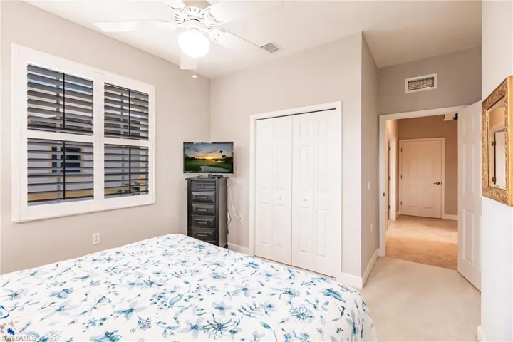 Bedroom with light colored carpet, a closet, and ceiling fan