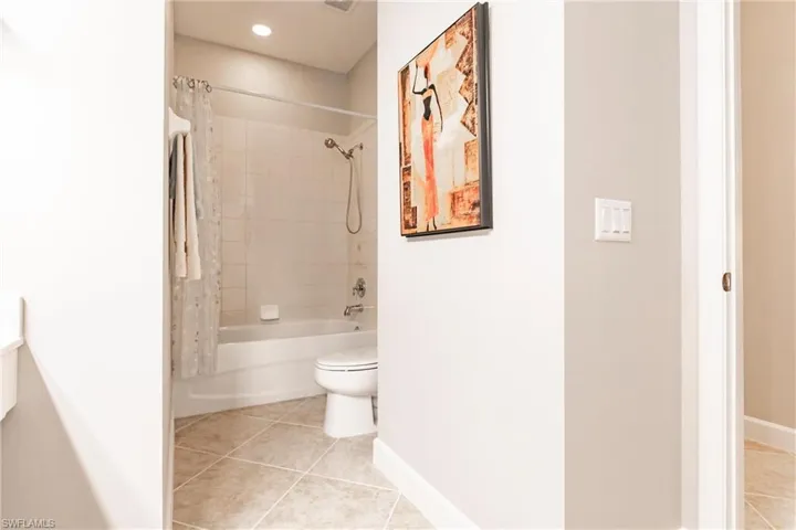 Full bath featuring shower / bathtub combination with curtain and light tile patterned floors
