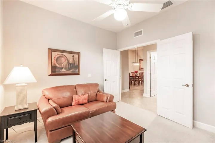 Living area with light carpet, a ceiling fan, and light tile patterned flooring