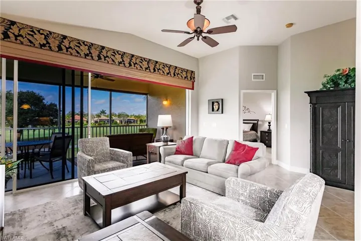Living area featuring lofted ceiling, tile patterned floors, and ceiling fan