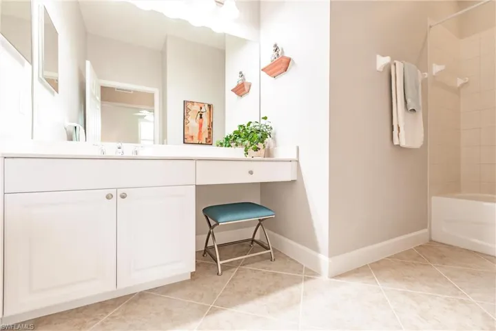 Full bathroom with light tile patterned floors, vanity, and washtub / shower combination