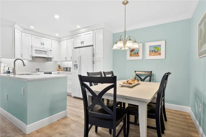 Dining room with light wood-style floors, suspended lighting, and crown molding