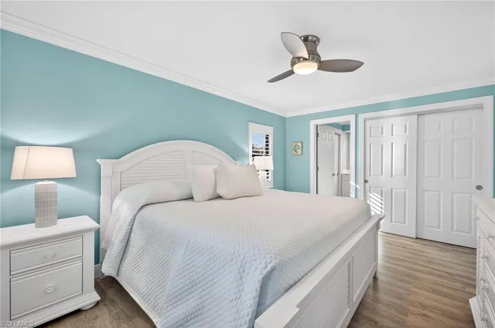 Primary Bedroom with crown molding, light wood-style floors, a closet, and a ceiling fan