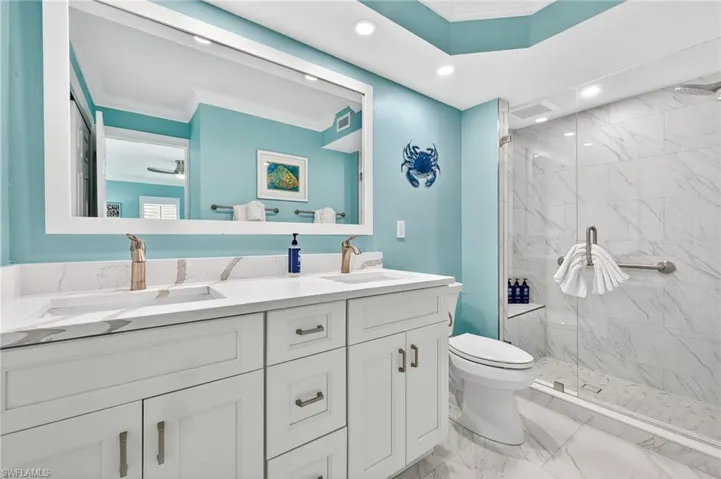 Primary Bathroom with ornamental molding, double vanity, a marble finish shower, light marble finish flooring, and recessed lighting