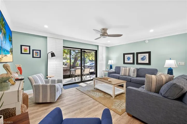 Living room with crown molding, wood finished floors, ceiling fan, and recessed lighting
