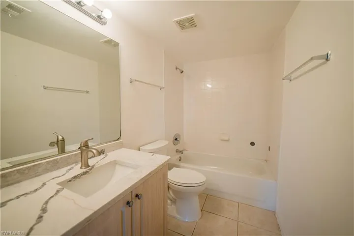 Full bath featuring vanity, bathtub / shower combination, and light tile patterned flooring