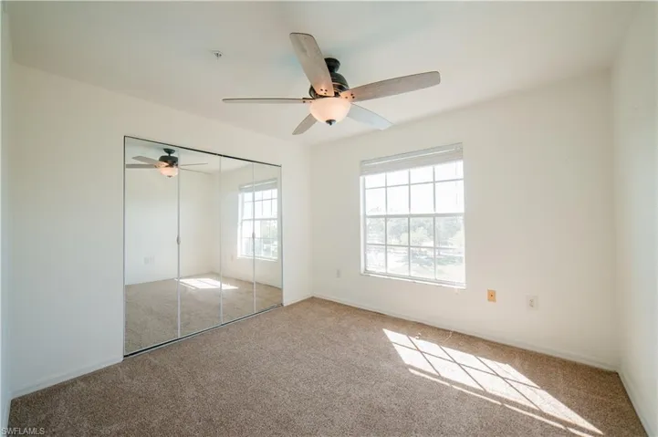 Unfurnished bedroom with carpet, a closet, and a ceiling fan