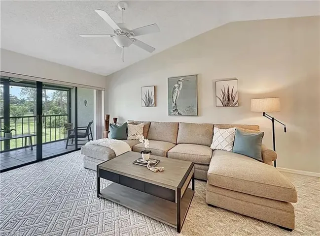 Living area featuring lofted ceiling, light carpet, a textured ceiling, and a ceiling fan