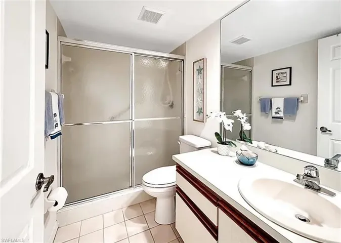 Full bath featuring light tile patterned flooring, vanity, and a shower stall