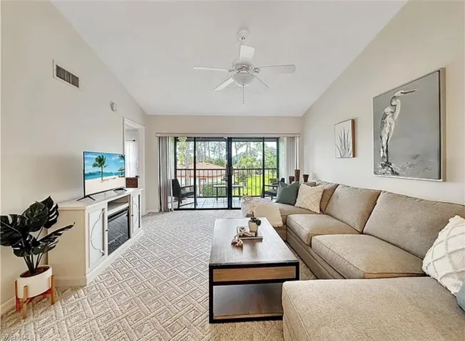 Living room with light carpet, a ceiling fan, and high vaulted ceiling