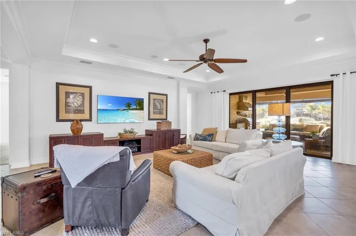 Living room featuring a tray ceiling, crown molding, ceiling fan, and light tile  flooring