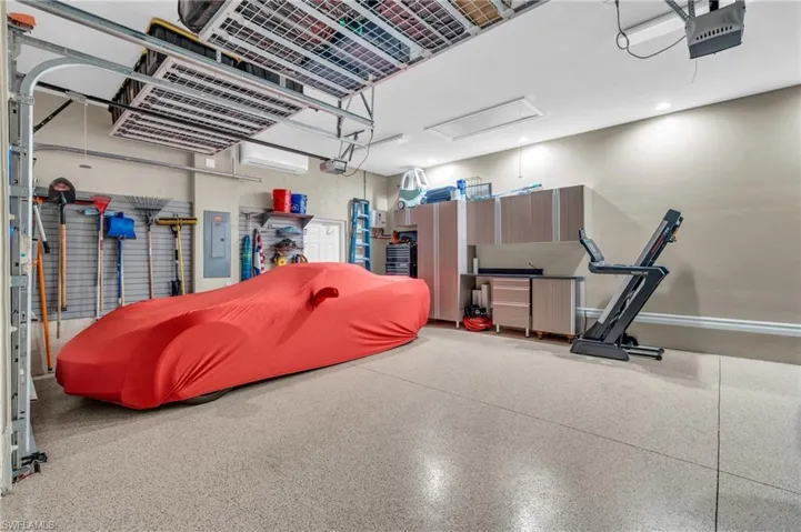 Garage featuring a garage door opener, electric panel, and a wall mounted AC