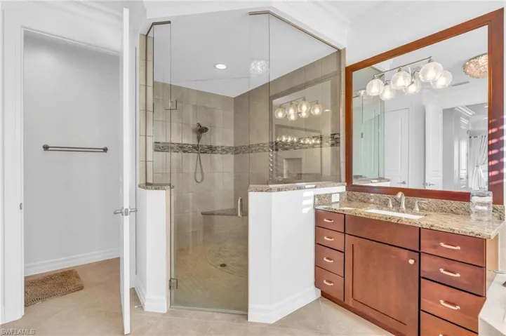 Bathroom with an enclosed shower, vanity, tile patterned flooring, and ornamental molding