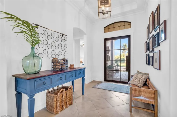 Foyer featuring light tile patterned flooring, crown molding, and a high ceiling
