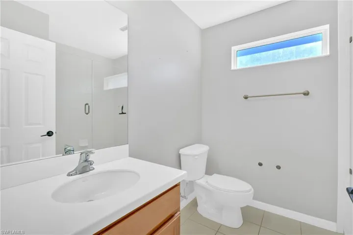 Full bath with vanity, an enclosed shower, and light tile patterned floors