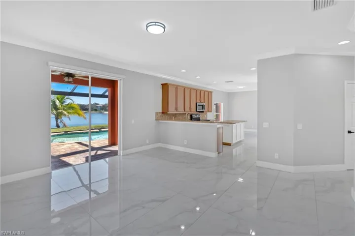 Unfurnished living room featuring crown molding, a water view, ceiling fan, recessed lighting, and light marble finish floors