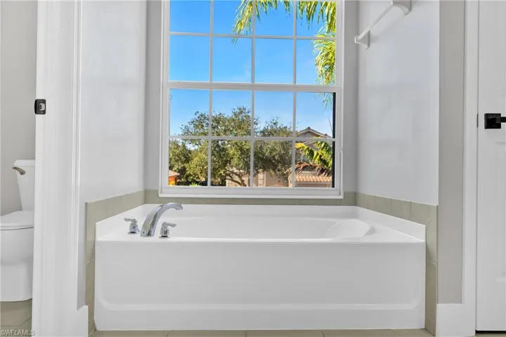 Bathroom with a garden tub and light tile patterned flooring