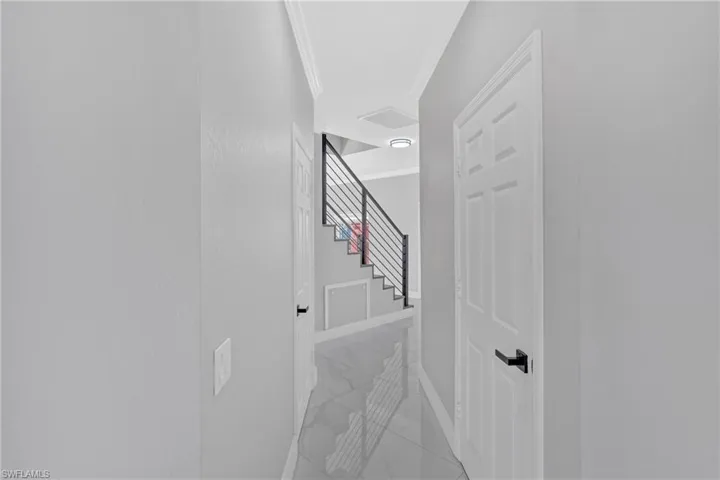 Corridor featuring ornamental molding and light marble finish floors