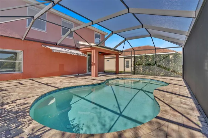 Outdoor pool featuring a sunroom, a patio, and glass enclosure