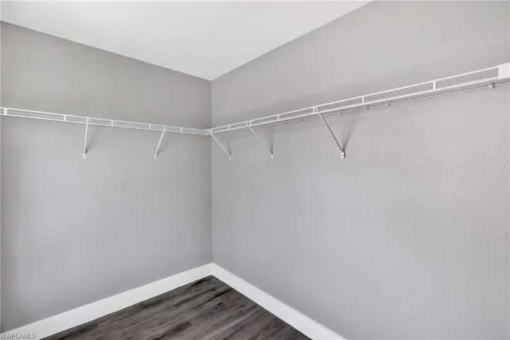 Walk in closet with dark wood-type flooring