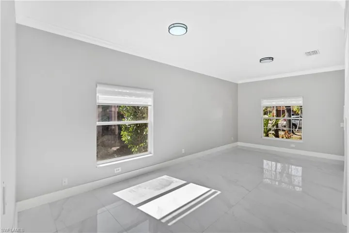 Unfurnished room with ornamental molding and marble finish flooring