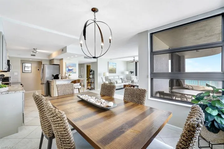 Tiled dining room with ceiling fan with notable chandelier