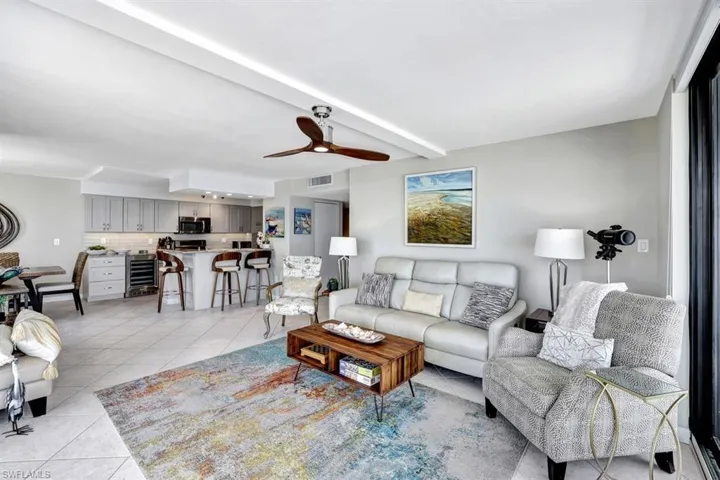 Living room featuring beam ceiling, wine cooler, ceiling fan, and light tile patterned flooring