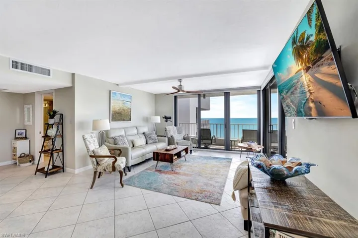 Tiled living room featuring a wall of windows and ceiling fan