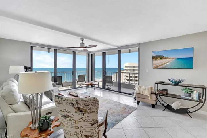 Tiled living room featuring floor to ceiling windows and ceiling fan