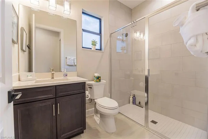 Bathroom with tile patterned flooring, vanity, a shower with shower door, and toilet