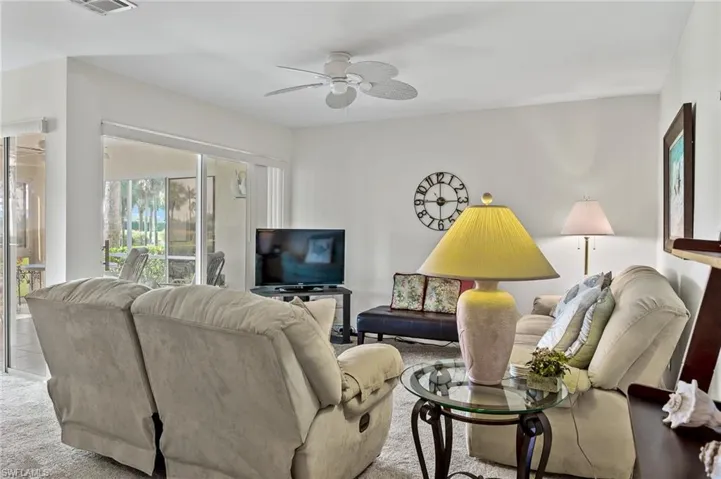 Living area featuring carpet flooring, visible vents, and ceiling fan