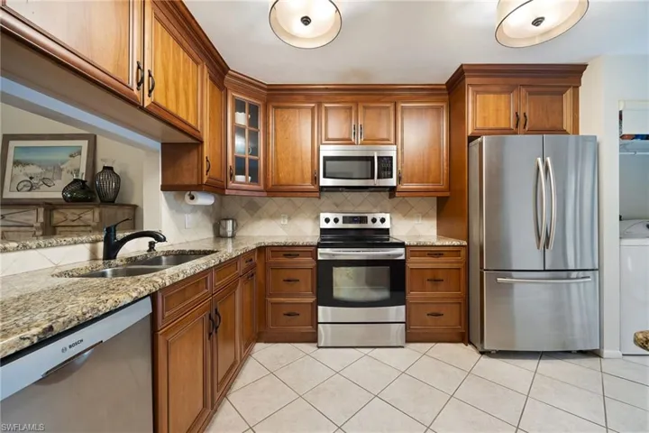 Kitchen featuring Custome wood fcabinetry, stainless steel appliances, light stone counters, and washer / dryer