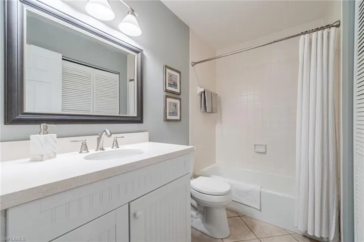 Full bathroom featuring a closet, vanity, shower / bathtub combination with curtain, and light tile patterned floors