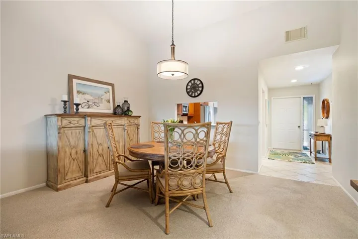 Dining space with light carpet, vaulted ceiling, and recessed lighting
