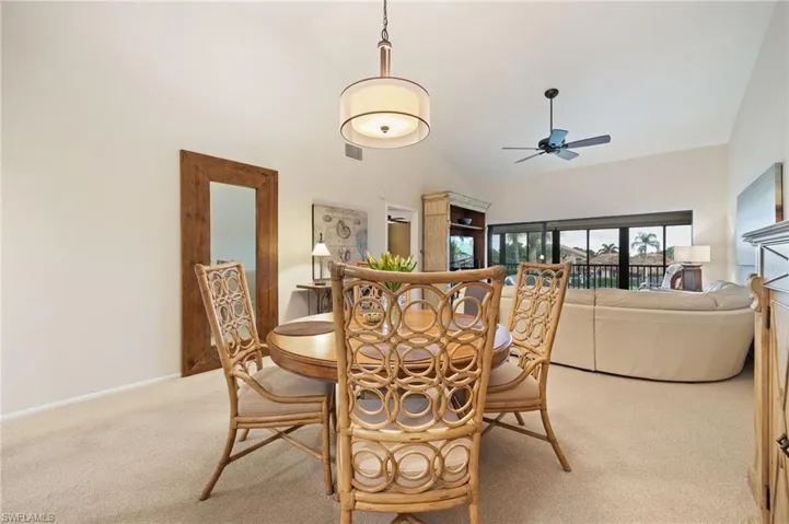 Dining area with light colored carpet, vaulted ceiling, and a ceiling fan