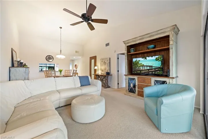 Carpeted living area with ceiling fan and lofted ceiling