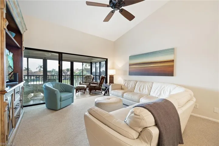 Living area featuring vaulted ceiling, a ceiling fan, and light colored carpet
