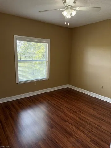 Unfurnished room featuring a ceiling fan, dark wood finished floors, and a textured ceiling